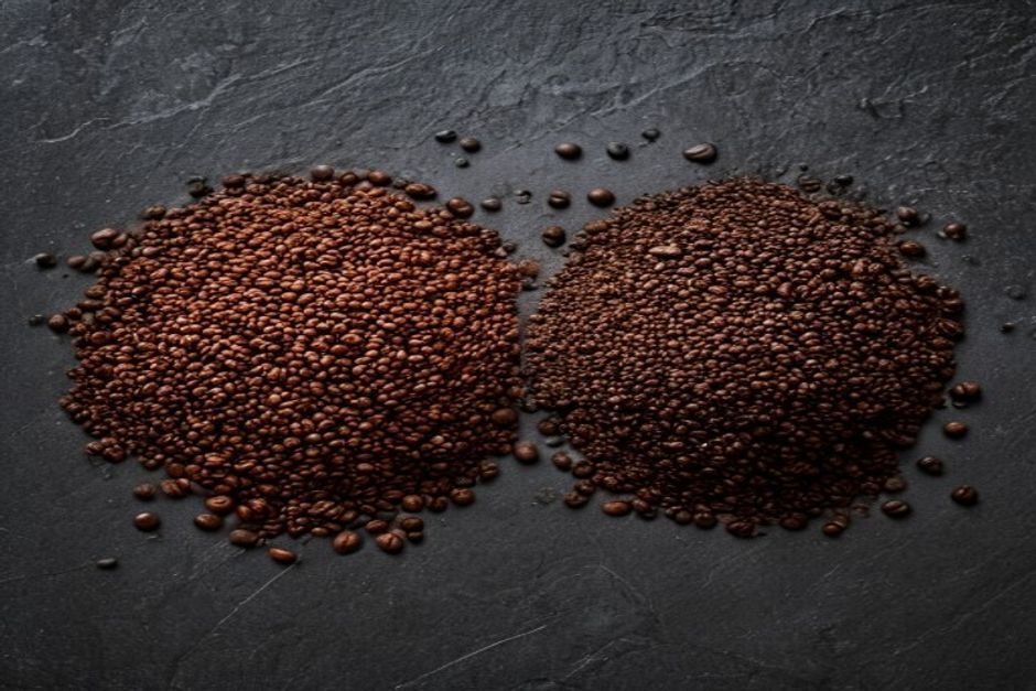 Dos montones de café molido, uno grueso y otro fino, sobre pizarra