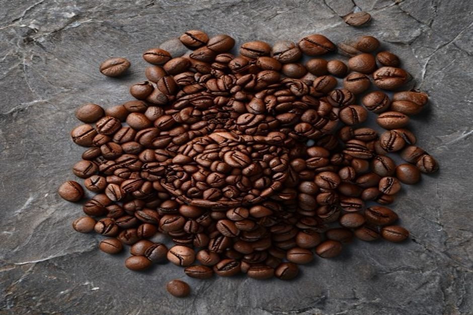 Granos de café tostados esparcidos sobre una superficie de pizarra