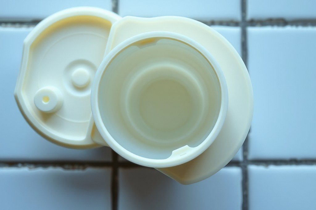 Depósito de leche de plástico con la tapa abierta y el interior completamente vacío